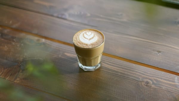 A single glass of latte with heart-shaped, calm focus and a rewarding pause after completing meaningful work